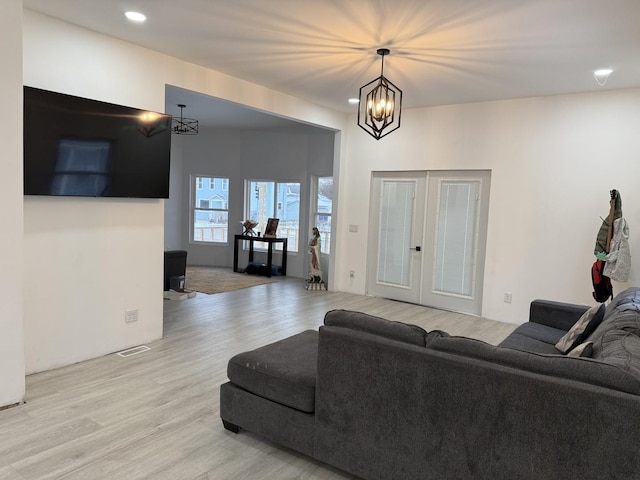 living room featuring an inviting chandelier, light wood-type flooring, and french doors