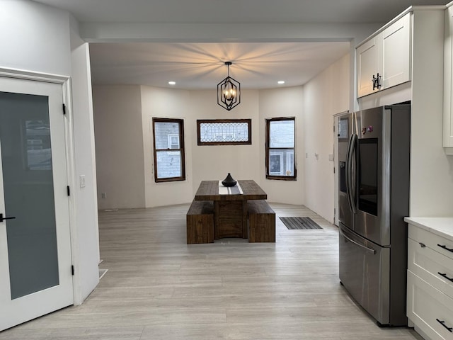 kitchen featuring white cabinetry, an inviting chandelier, hanging light fixtures, stainless steel fridge, and light hardwood / wood-style floors