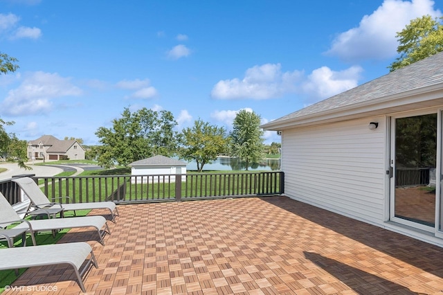 view of patio / terrace with a garage, a water view, and an outdoor structure