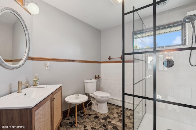 bathroom featuring a tile shower, vanity, and toilet