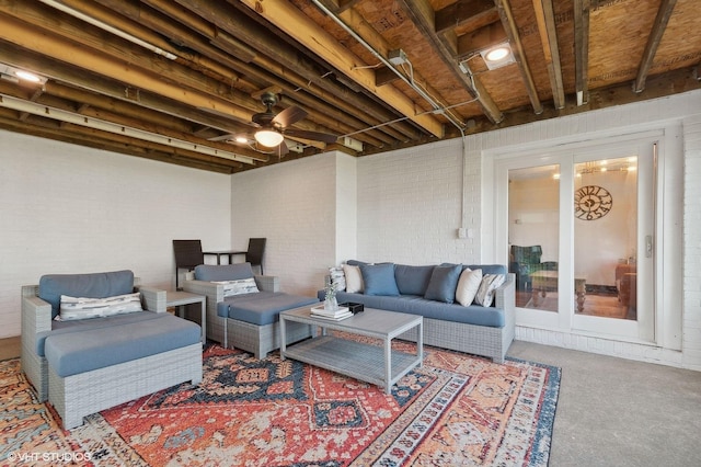 living room with brick wall, carpet floors, and ceiling fan