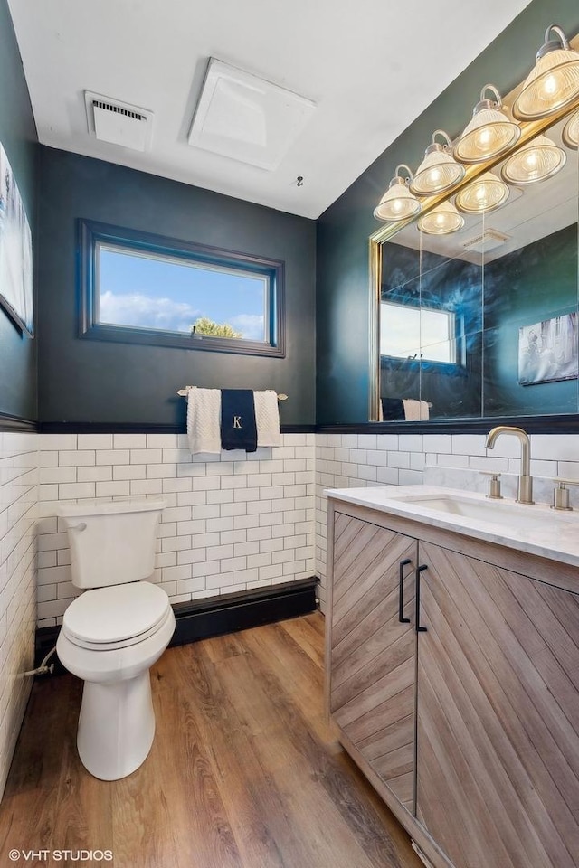 bathroom with hardwood / wood-style flooring, vanity, tile walls, and toilet