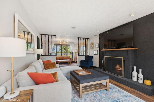 living room featuring hardwood / wood-style flooring, a brick fireplace, and a textured ceiling