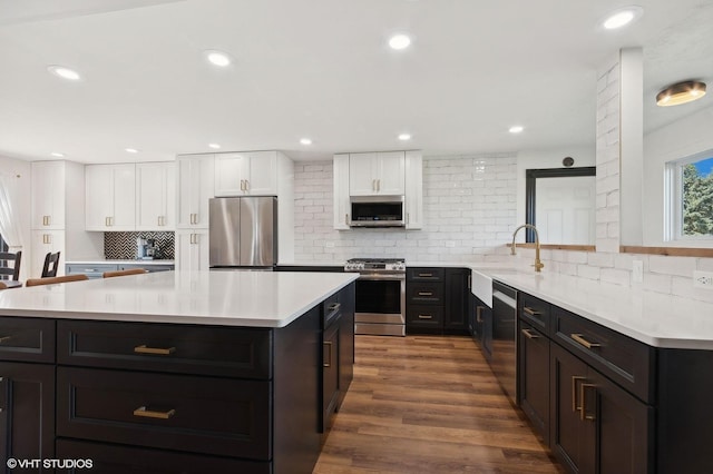 kitchen with sink, white cabinetry, dark hardwood / wood-style floors, a kitchen island, and stainless steel appliances