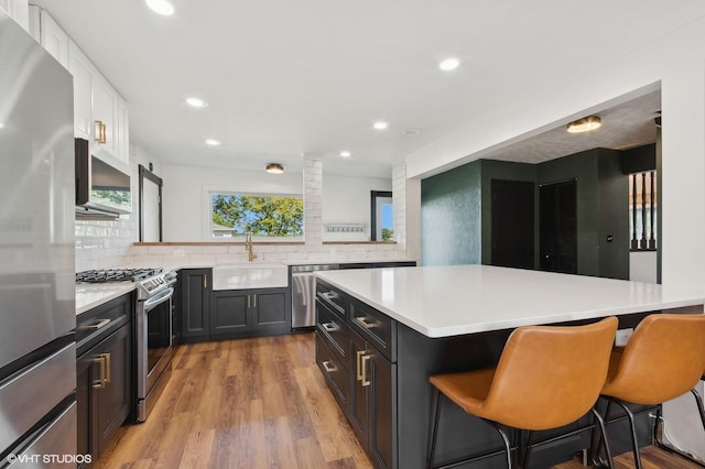 kitchen with a kitchen island, tasteful backsplash, sink, a kitchen bar, and stainless steel appliances