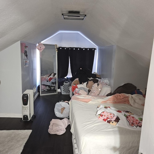 bedroom with vaulted ceiling, wood finished floors, baseboards, and a textured ceiling