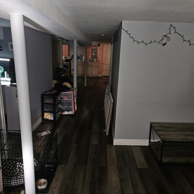 corridor featuring wood finished floors, baseboards, and ornate columns