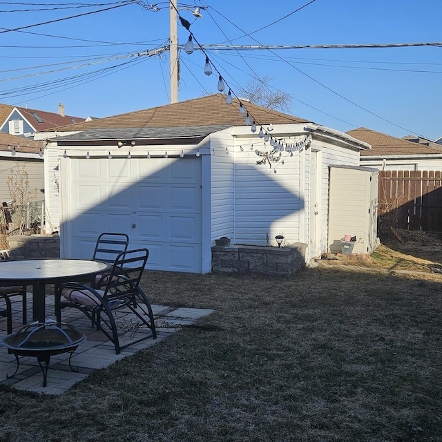 view of yard featuring a patio, fence, outdoor dining area, an outdoor structure, and a garage