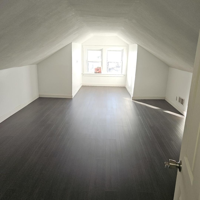 bonus room with visible vents, baseboards, vaulted ceiling, a textured ceiling, and dark wood-style flooring