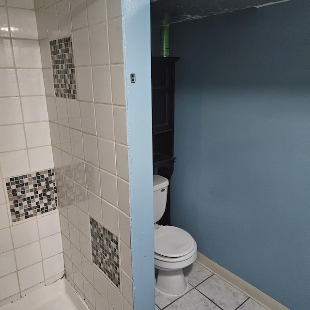 bathroom with baseboards, tiled shower, and toilet