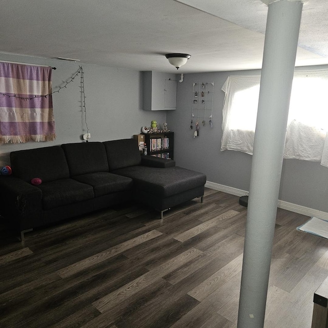 living area featuring ornate columns, baseboards, and wood finished floors