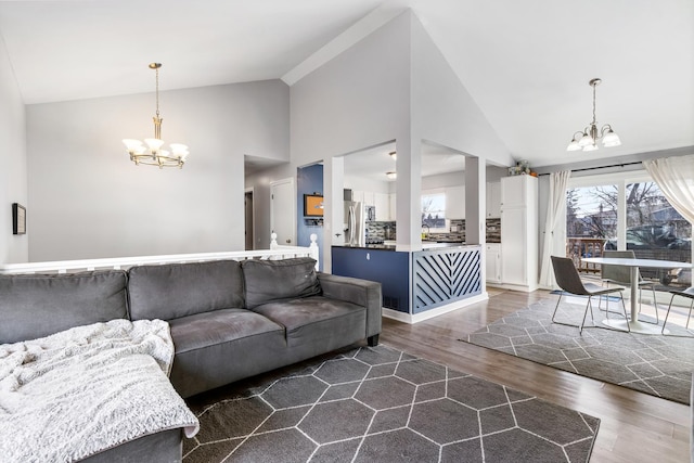 living room with high vaulted ceiling, dark wood-type flooring, and an inviting chandelier