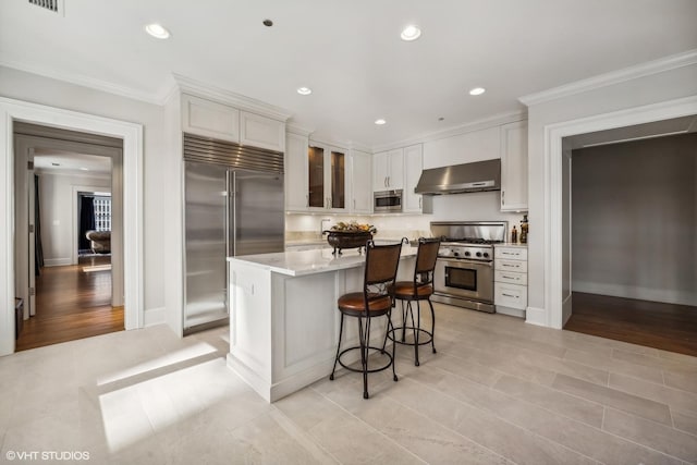 kitchen featuring built in appliances, white cabinetry, and crown molding