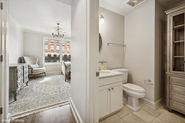 bathroom with tile patterned flooring, vanity, ornamental molding, a notable chandelier, and toilet