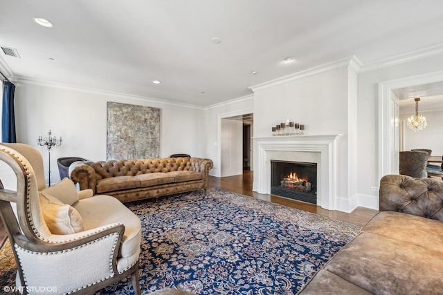 living room with wood-type flooring, ornamental molding, and a chandelier