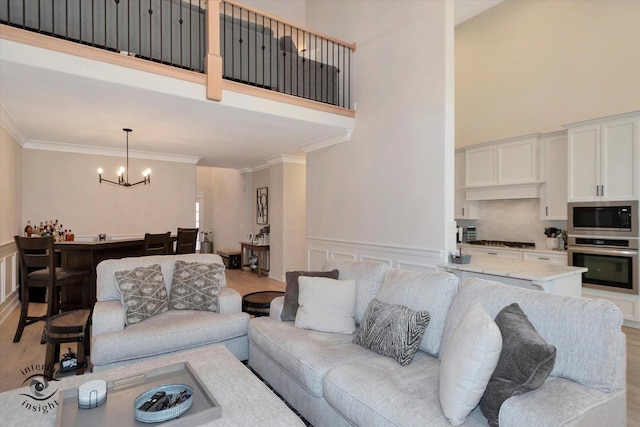 20375 Grosse Point Dr, Frankfort, IL 60423 - living area with a towering ceiling, a chandelier, ornamental molding, light wood-type flooring, and wainscoting