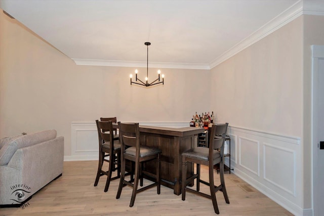 20375 Grosse Point Dr, Frankfort, IL 60423 - dining area with a decorative wall, a dry bar, a chandelier, crown molding, and light wood-style floors