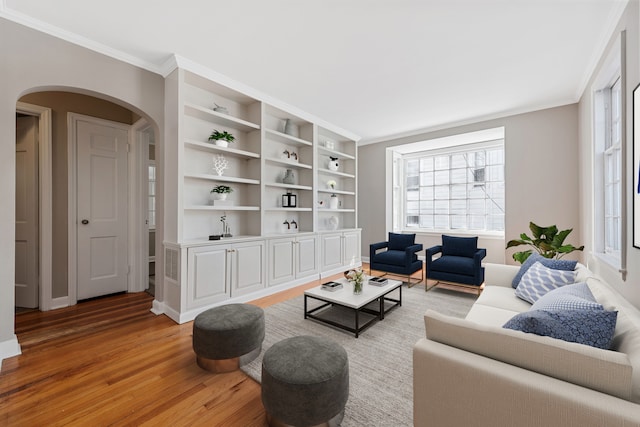 living area featuring arched walkways, wood finished floors, and ornamental molding