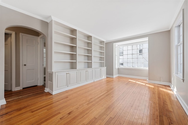 unfurnished living room featuring light wood-type flooring, baseboards, arched walkways, and ornamental molding