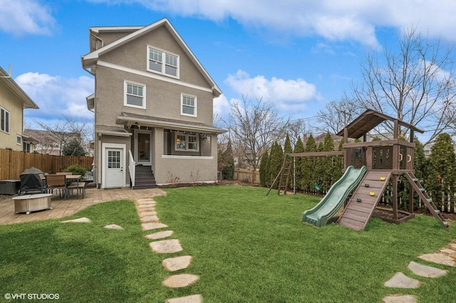 back of property featuring a playground, a lawn, and a patio area