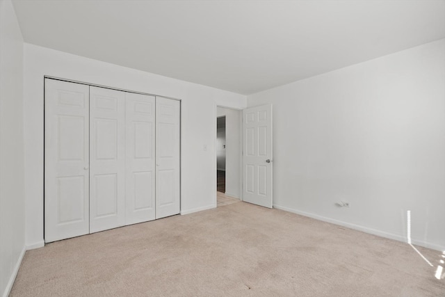 unfurnished bedroom featuring a closet and light carpet