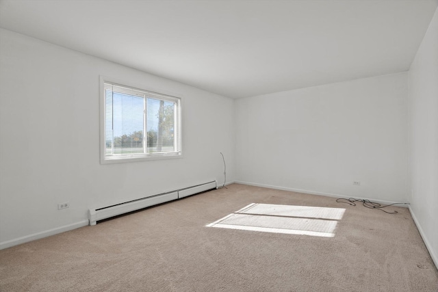 spare room with a baseboard heating unit and light carpet