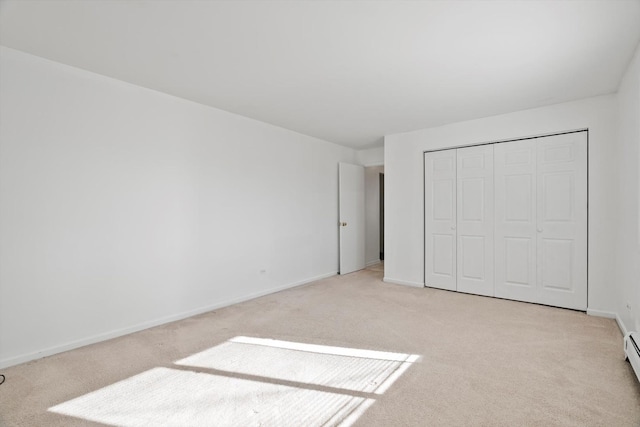 unfurnished bedroom featuring baseboard heating, light colored carpet, and a closet