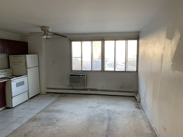 kitchen with a baseboard radiator, a wall mounted AC, ceiling fan, and white range with electric cooktop