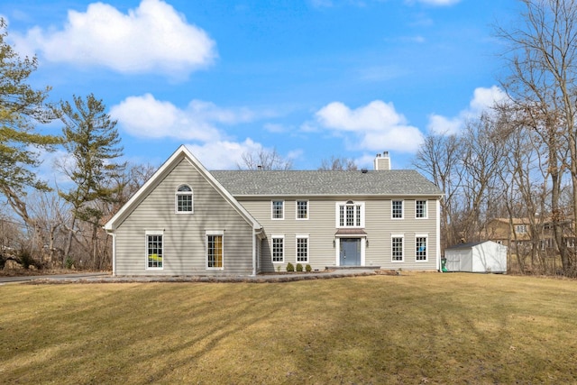 colonial home featuring an outbuilding, a shed, a chimney, and a front yard