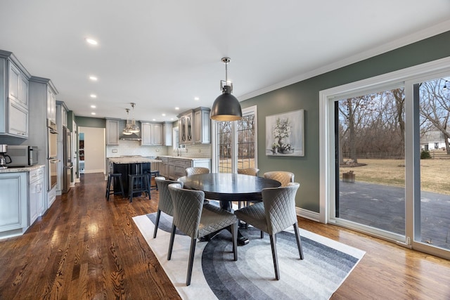 dining space with dark wood-style floors, a healthy amount of sunlight, baseboards, and ornamental molding