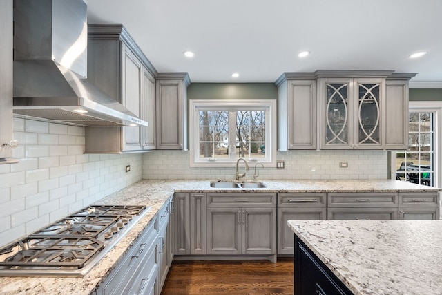 kitchen with stainless steel gas cooktop, gray cabinetry, wall chimney range hood, and a sink