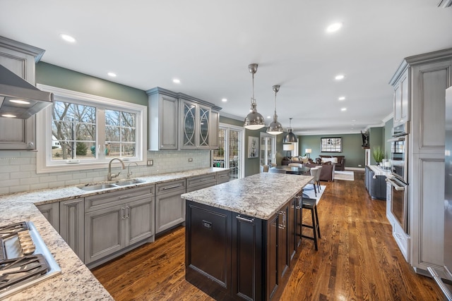 kitchen featuring gray cabinetry, open floor plan, appliances with stainless steel finishes, dark wood-style floors, and a sink