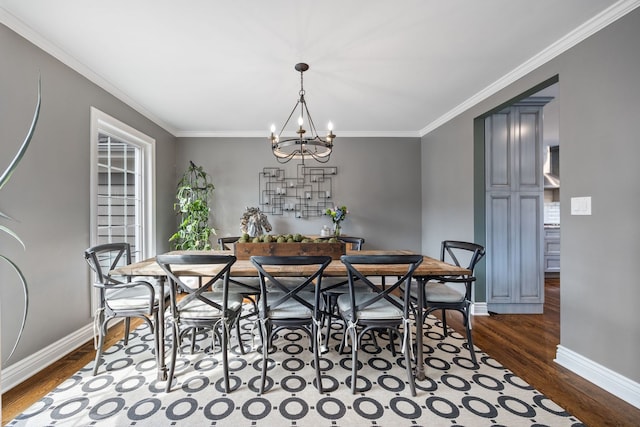 dining area featuring an inviting chandelier, dark wood-style floors, baseboards, and ornamental molding