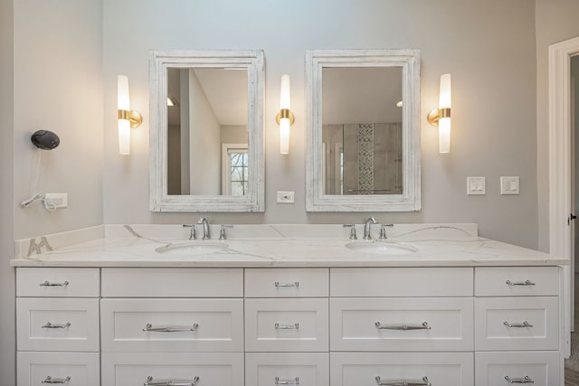 full bath featuring double vanity, a tile shower, and a sink