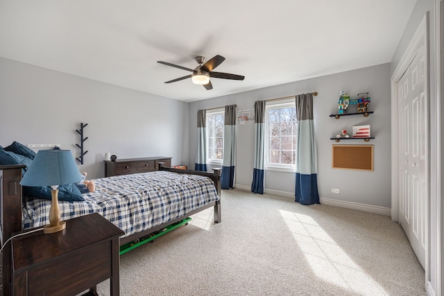 bedroom with ceiling fan, light colored carpet, a closet, and baseboards