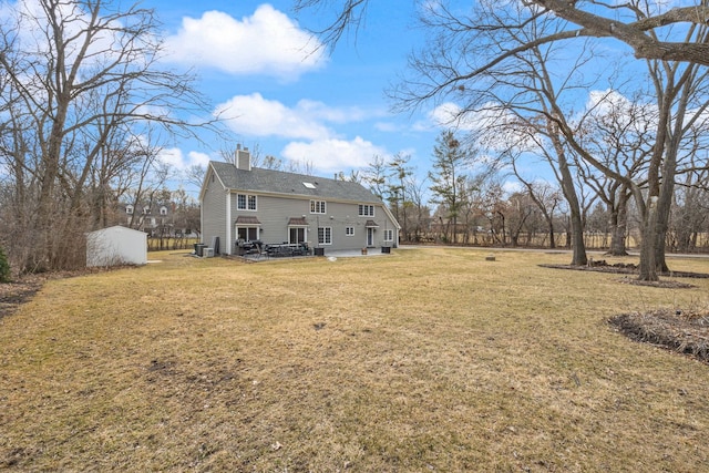 rear view of property with an outbuilding, a lawn, and a chimney