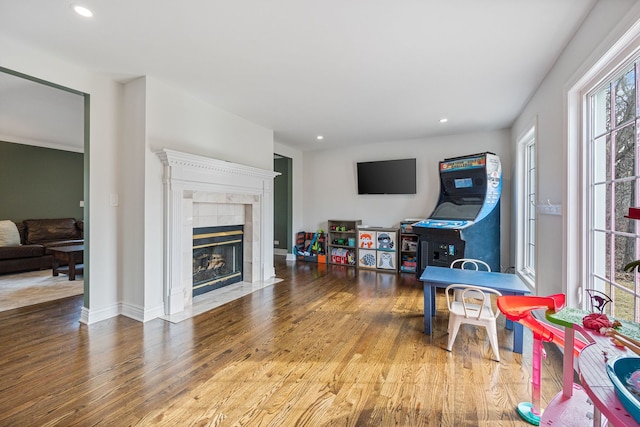 game room featuring recessed lighting, baseboards, wood finished floors, and a tiled fireplace