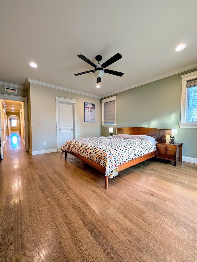 bedroom with crown molding, ceiling fan, and light hardwood / wood-style flooring