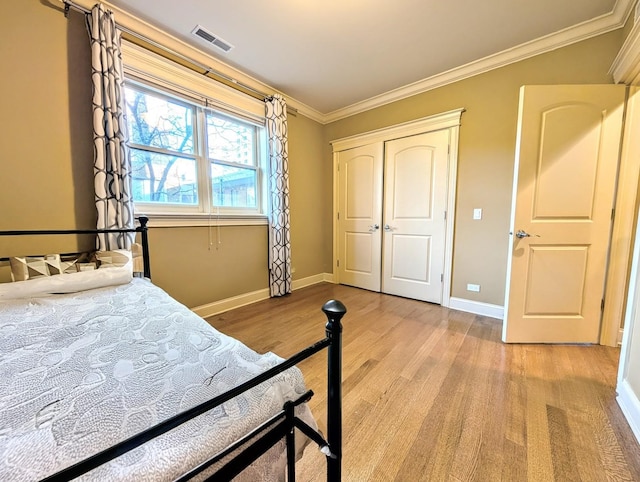 bedroom featuring light hardwood / wood-style flooring, ornamental molding, and a closet