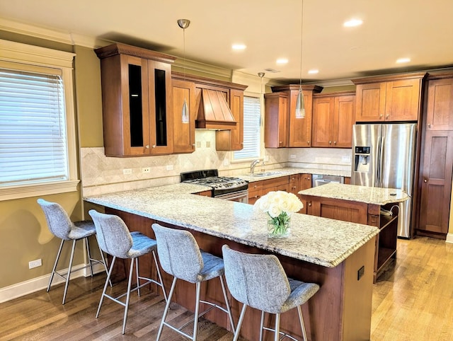 kitchen with pendant lighting, premium range hood, appliances with stainless steel finishes, a center island, and a kitchen bar