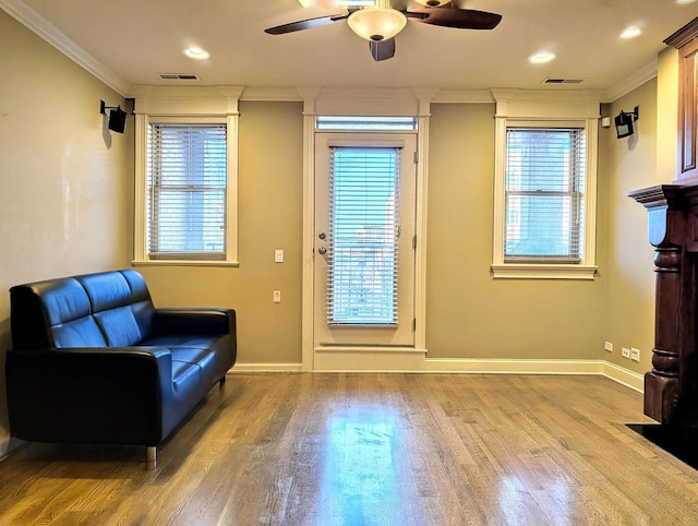 living area featuring crown molding, light hardwood / wood-style floors, and ceiling fan