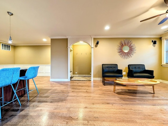 living area with ornamental molding, ceiling fan, and light hardwood / wood-style flooring