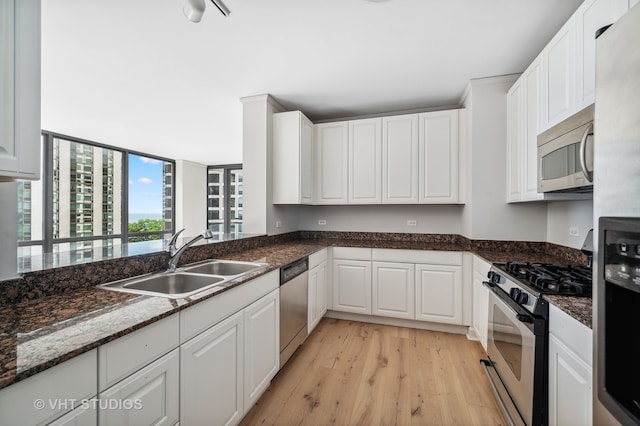 kitchen with sink, stainless steel appliances, white cabinetry, and dark stone countertops