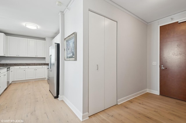 kitchen with white cabinets, light hardwood / wood-style floors, stainless steel appliances, and ornamental molding