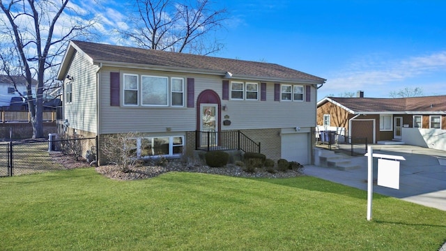 raised ranch with driveway, a front lawn, an attached garage, and fence