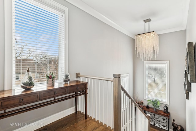 hall with plenty of natural light, dark wood finished floors, an upstairs landing, and crown molding