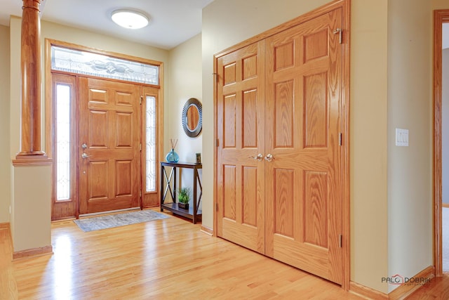 entrance foyer featuring ornate columns and light hardwood / wood-style flooring