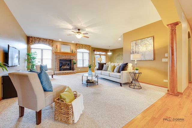 living room featuring ceiling fan, a healthy amount of sunlight, a fireplace, and ornate columns