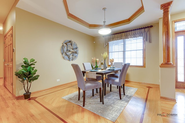 dining room with crown molding, a tray ceiling, and ornate columns