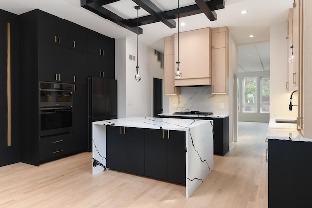 kitchen featuring black refrigerator, decorative light fixtures, sink, double wall oven, and a center island